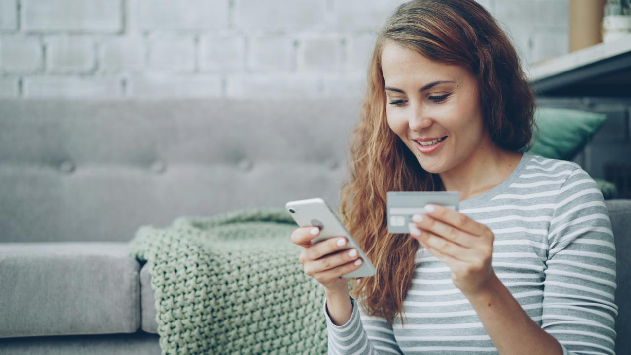 Wanita menggunakan smartphone dan kartu kredit untuk belanja online