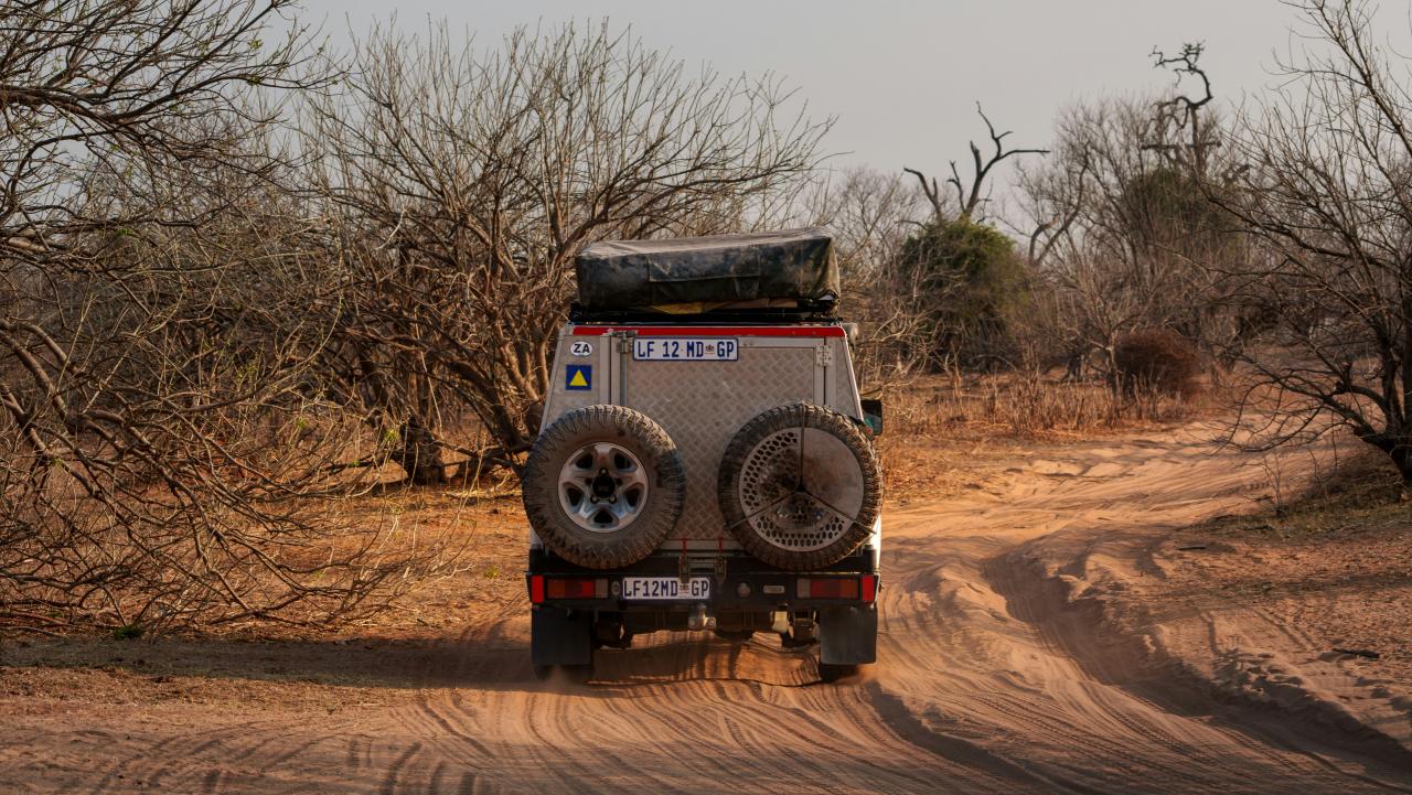 An off-road vehicle drives on a dusty track.